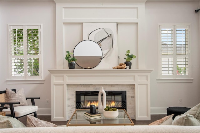 living room featuring a glass covered fireplace, baseboards, and a healthy amount of sunlight