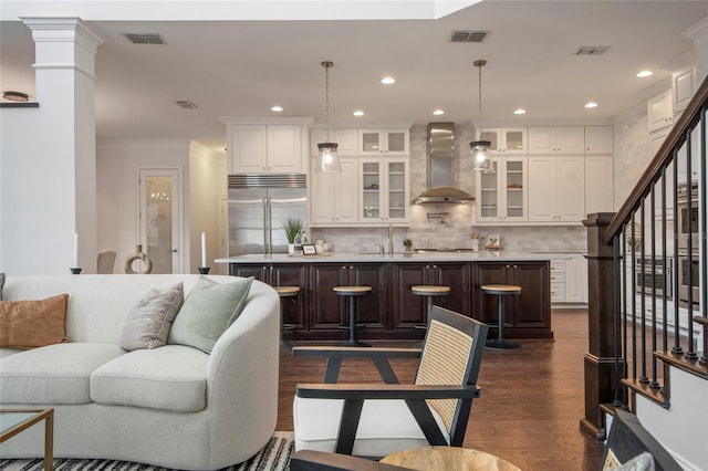 living area with crown molding, dark wood-style floors, visible vents, and stairway