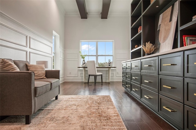 living area with dark wood-style floors, a decorative wall, ornamental molding, and a wainscoted wall