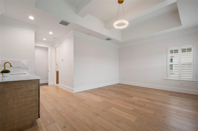 empty room with baseboards, crown molding, light wood-style floors, visible vents, and a sink