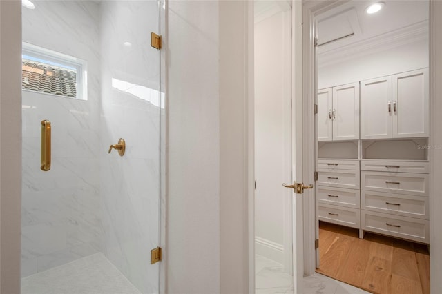 bathroom featuring marble finish floor, a marble finish shower, and ornamental molding