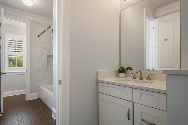 full bath with baseboards, crown molding, vanity, wood finished floors, and shower / bathtub combination