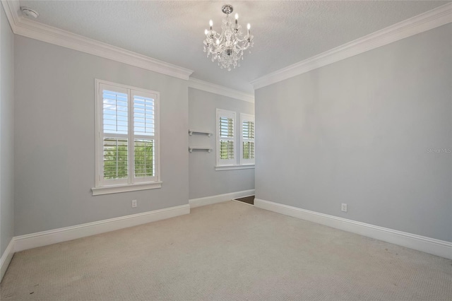 carpeted spare room with a notable chandelier, baseboards, and crown molding