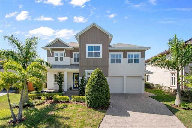 view of front of property featuring a front lawn, decorative driveway, and an attached garage