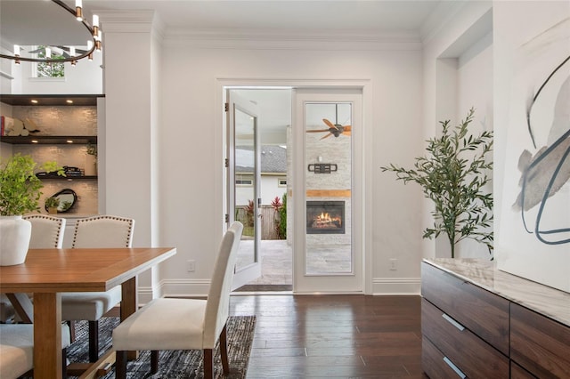 doorway to outside with a notable chandelier, dark wood-style floors, ornamental molding, and a healthy amount of sunlight