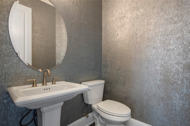 bathroom featuring baseboards, a sink, and toilet