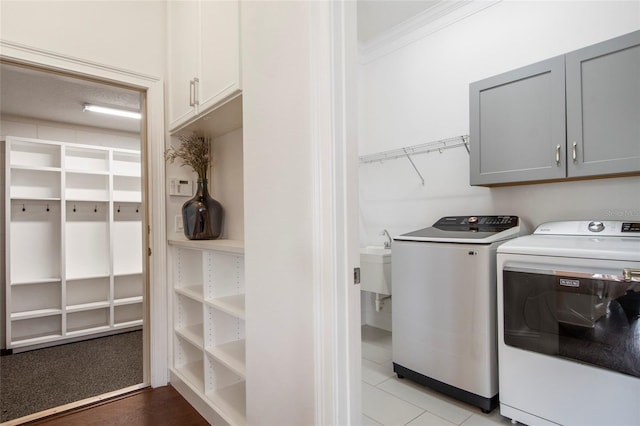 clothes washing area with cabinet space, separate washer and dryer, crown molding, and a sink
