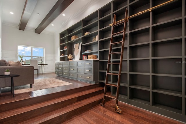 interior space with a decorative wall, dark wood-style floors, crown molding, beamed ceiling, and wainscoting