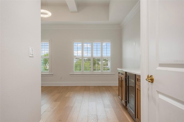 empty room featuring light wood-style floors, crown molding, and a wealth of natural light