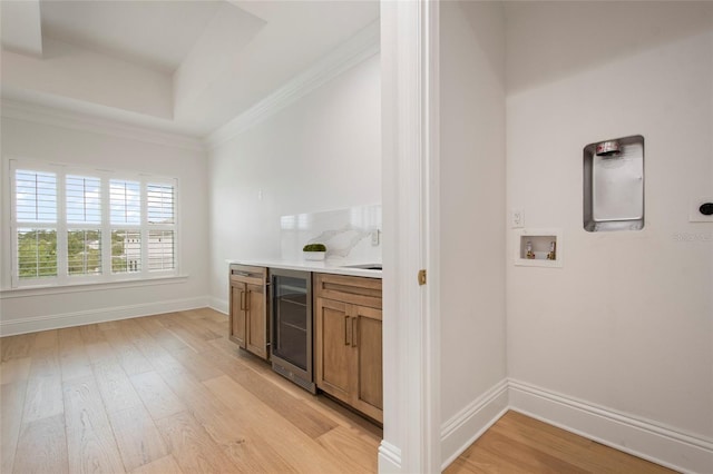bar with wine cooler, baseboards, light wood-type flooring, and crown molding
