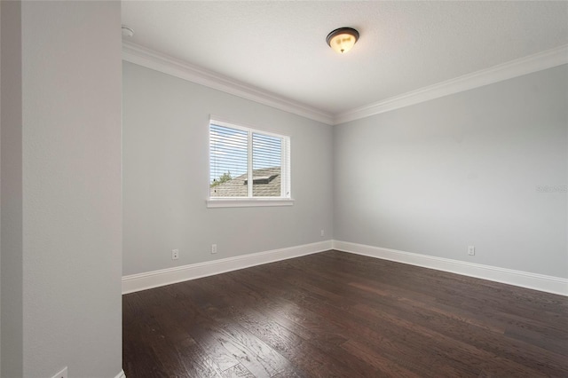 empty room with baseboards, ornamental molding, and dark wood finished floors