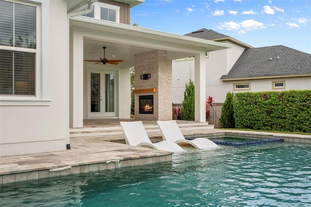 view of swimming pool with a ceiling fan, a warm lit fireplace, a patio, french doors, and a fenced in pool