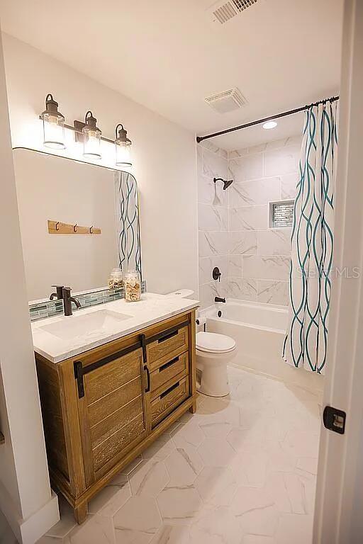 full bathroom with toilet, shower / tub combo with curtain, and vanity