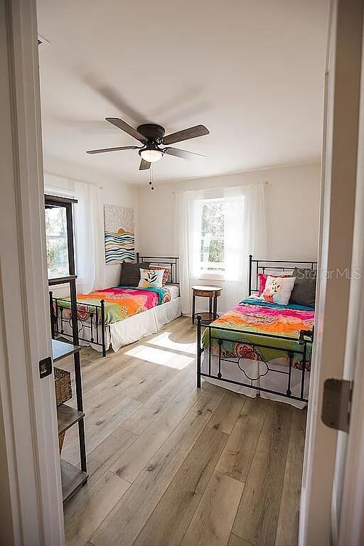 bedroom with multiple windows, ceiling fan, and light hardwood / wood-style flooring