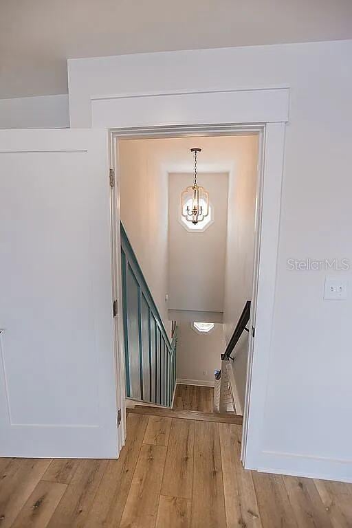 stairway with a notable chandelier and wood-type flooring