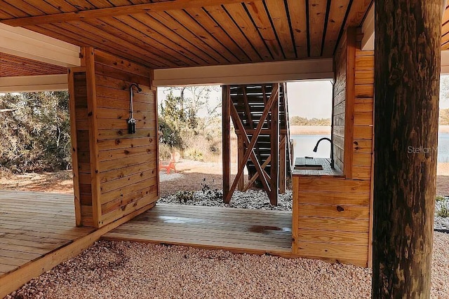 doorway to outside with a water view, wood ceiling, and wood walls