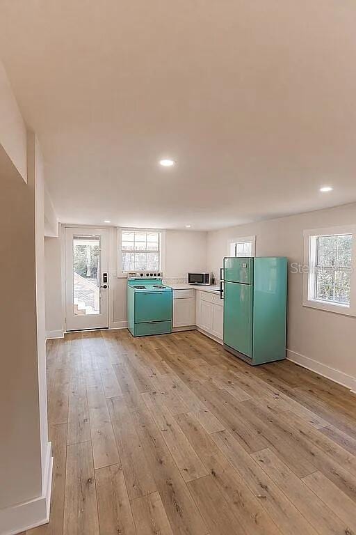 kitchen with light hardwood / wood-style floors, plenty of natural light, refrigerator, and washer / dryer