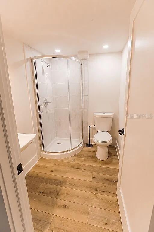 bathroom featuring toilet, hardwood / wood-style floors, and a shower with shower door