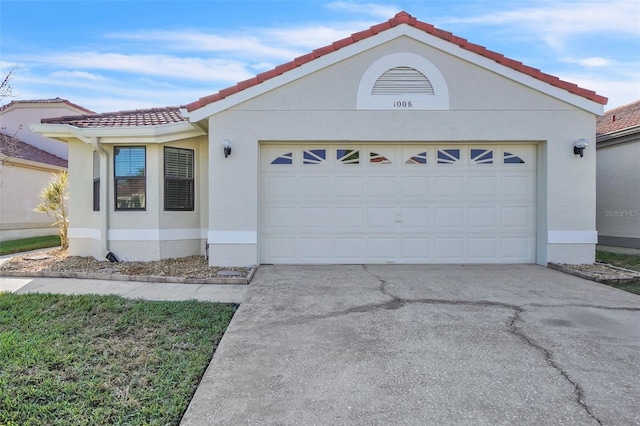 view of front of home with a tiled roof, concrete driveway, an attached garage, and stucco siding