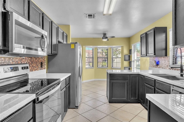 1008 Birkdale Trl, Winter Springs, FL 32708 - kitchen with light tile patterned floors, a peninsula, a sink, stainless steel appliances, and backsplash