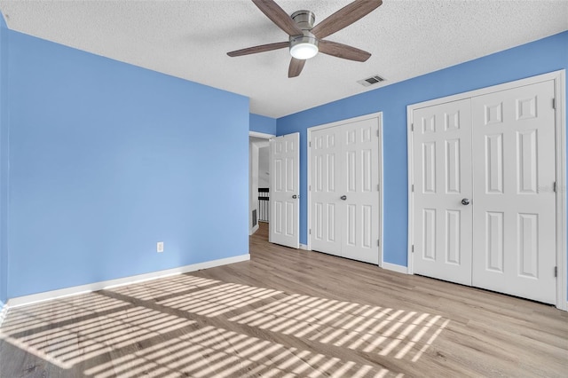1008 Birkdale Trl, Winter Springs, FL 32708 - unfurnished bedroom featuring two closets, visible vents, a textured ceiling, light wood-type flooring, and baseboards