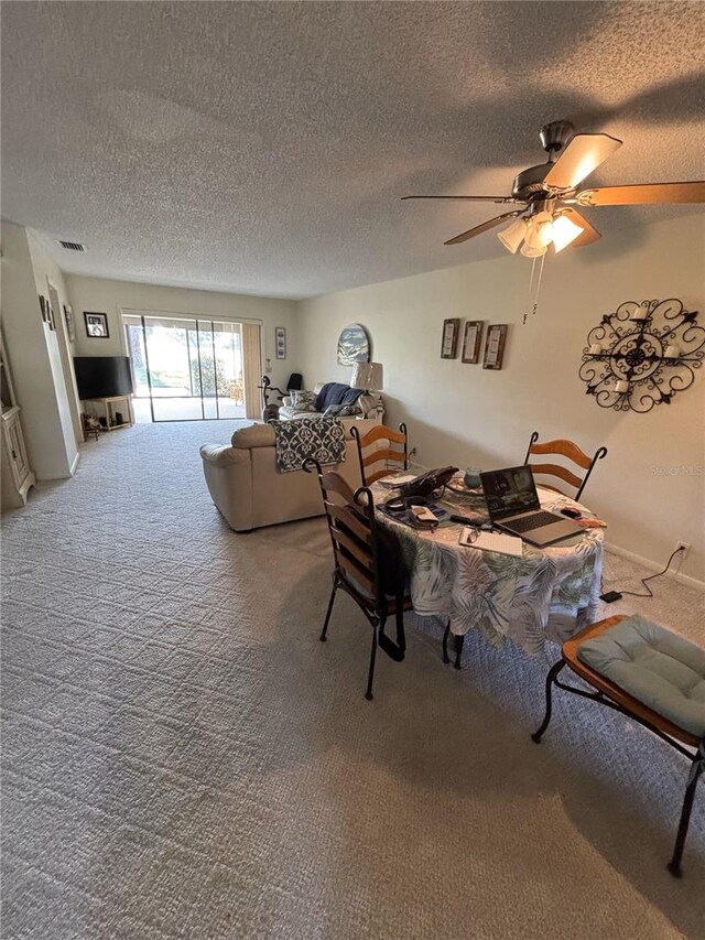 living room with a textured ceiling, ceiling fan, carpet flooring, and visible vents