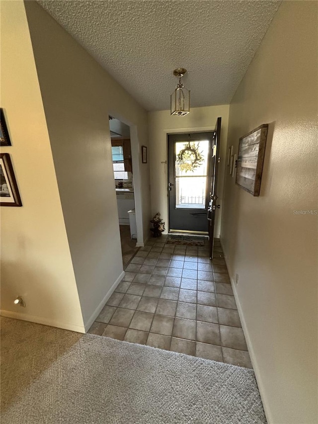 entryway with a textured ceiling, tile patterned flooring, and baseboards