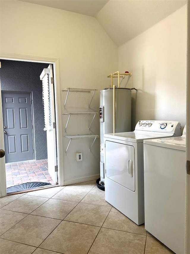 washroom featuring light tile patterned flooring, laundry area, baseboards, water heater, and washer and dryer