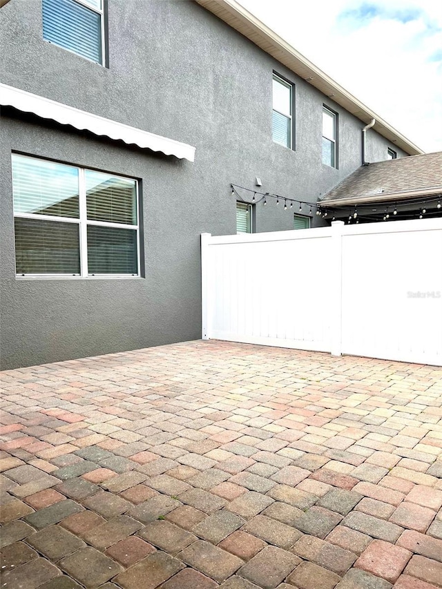 exterior space with fence, a patio, and stucco siding