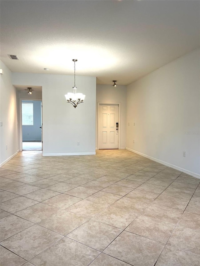 unfurnished room featuring baseboards, visible vents, a notable chandelier, and light tile patterned flooring