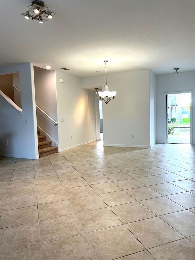 spare room with light tile patterned flooring, a notable chandelier, stairway, and baseboards