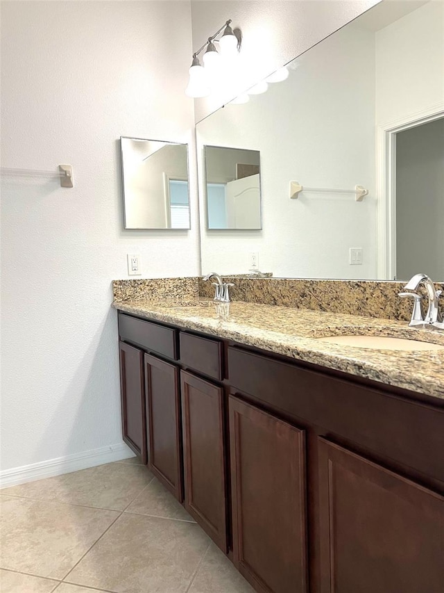 full bath with tile patterned flooring, a sink, baseboards, and double vanity