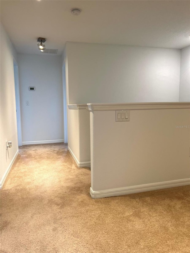 hallway featuring baseboards and light colored carpet