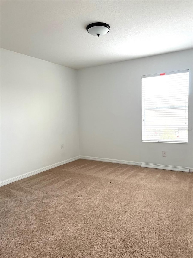 empty room with a textured ceiling, carpet, and baseboards