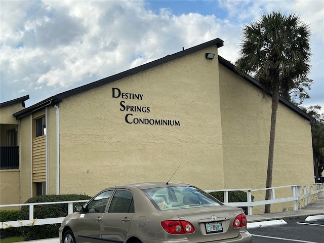 view of building exterior with uncovered parking and fence