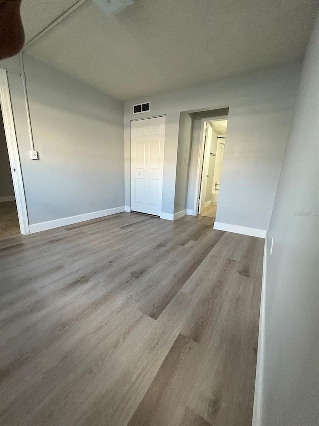 unfurnished bedroom featuring a closet, visible vents, light wood-style flooring, and baseboards