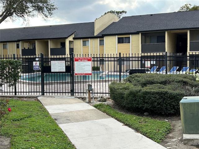 view of property's community with a pool and fence