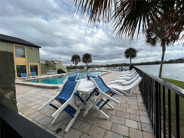 pool featuring a patio area and a water view