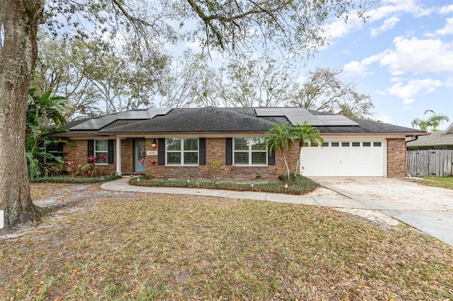 single story home featuring brick siding, an attached garage, fence, driveway, and a front lawn