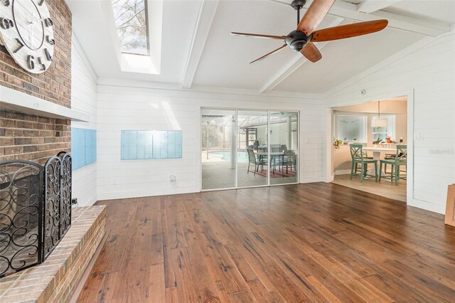 unfurnished living room with ceiling fan, lofted ceiling with skylight, a fireplace, and wood-type flooring