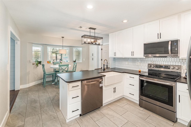 kitchen featuring appliances with stainless steel finishes, dark countertops, a peninsula, and decorative backsplash