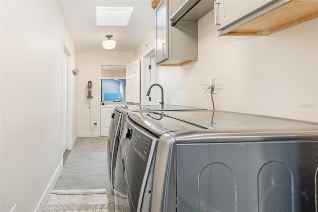 clothes washing area with washing machine and clothes dryer, cabinet space, and baseboards