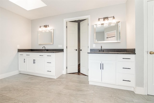 full bath with a sink, baseboards, and two vanities