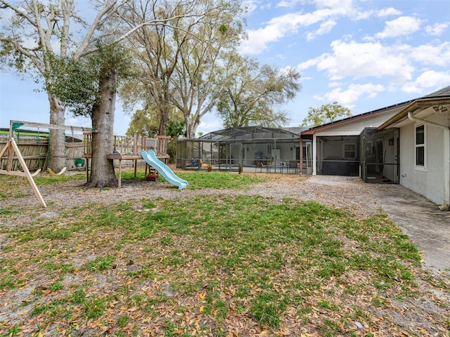 view of yard featuring a lanai, fence, and a playground