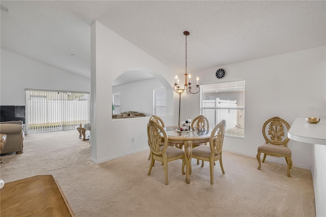 carpeted dining area with lofted ceiling, an inviting chandelier, and a textured ceiling