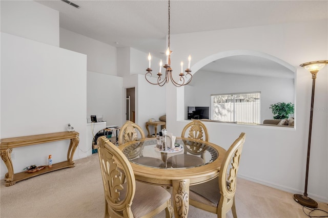 dining room featuring visible vents, arched walkways, light colored carpet, lofted ceiling, and an inviting chandelier