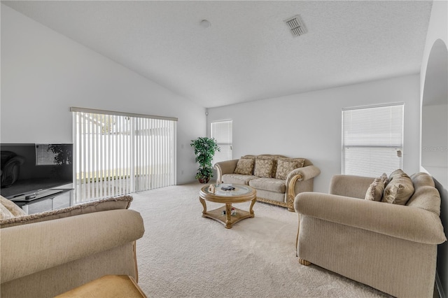 living room with vaulted ceiling, a textured ceiling, carpet, and visible vents