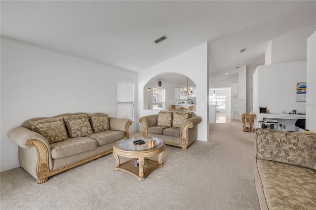 living area with light carpet, visible vents, arched walkways, vaulted ceiling, and a notable chandelier