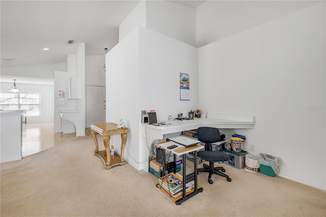 office featuring light carpet, vaulted ceiling, visible vents, and baseboards