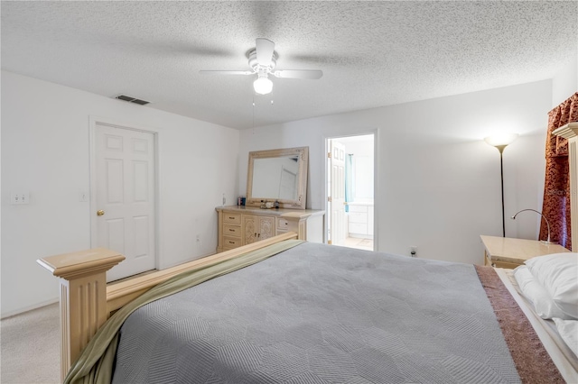 bedroom featuring light colored carpet, visible vents, a ceiling fan, a textured ceiling, and ensuite bath